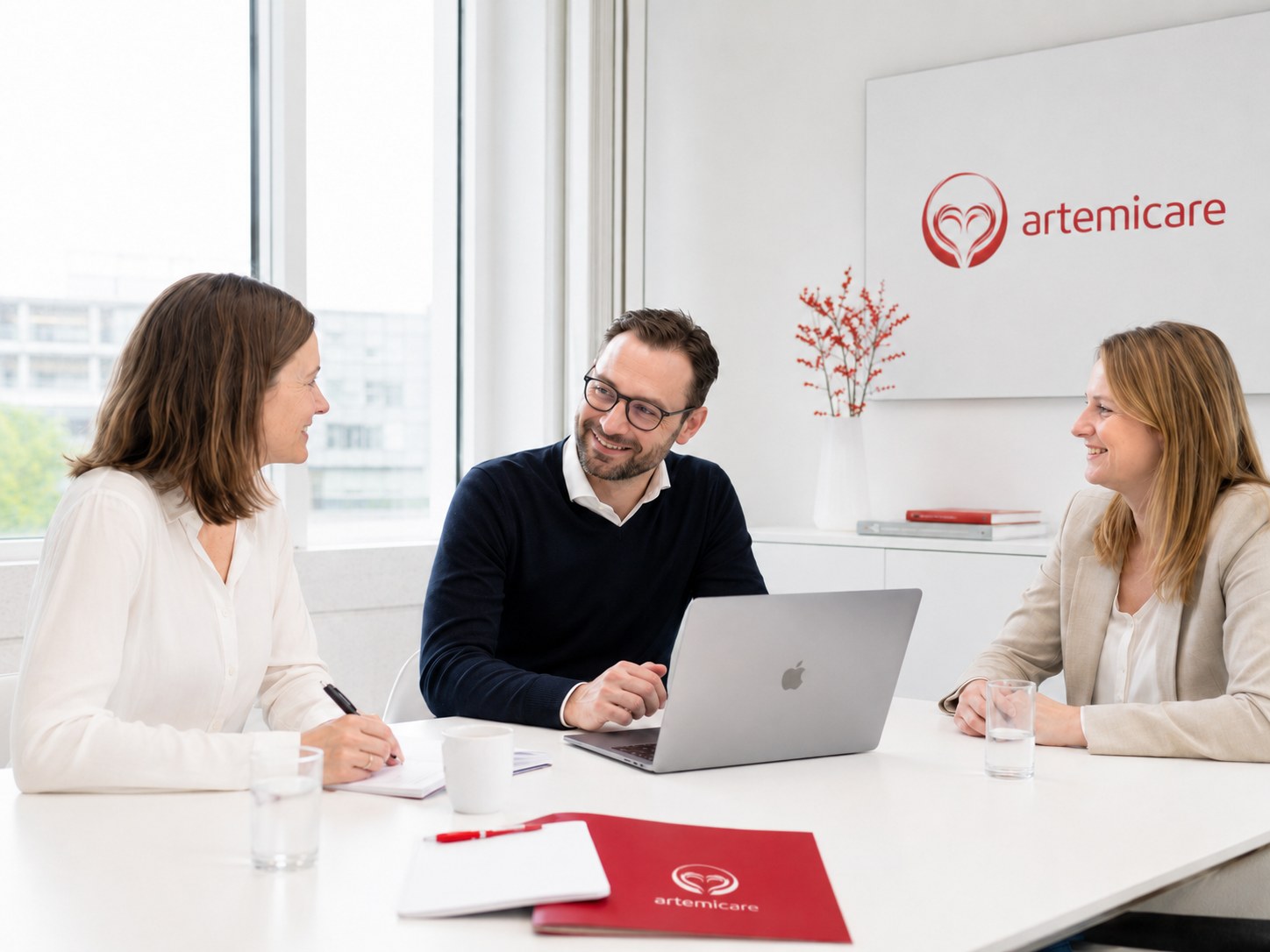 artemicare Unternehmensgespräch mit Laptop und Unterlagen