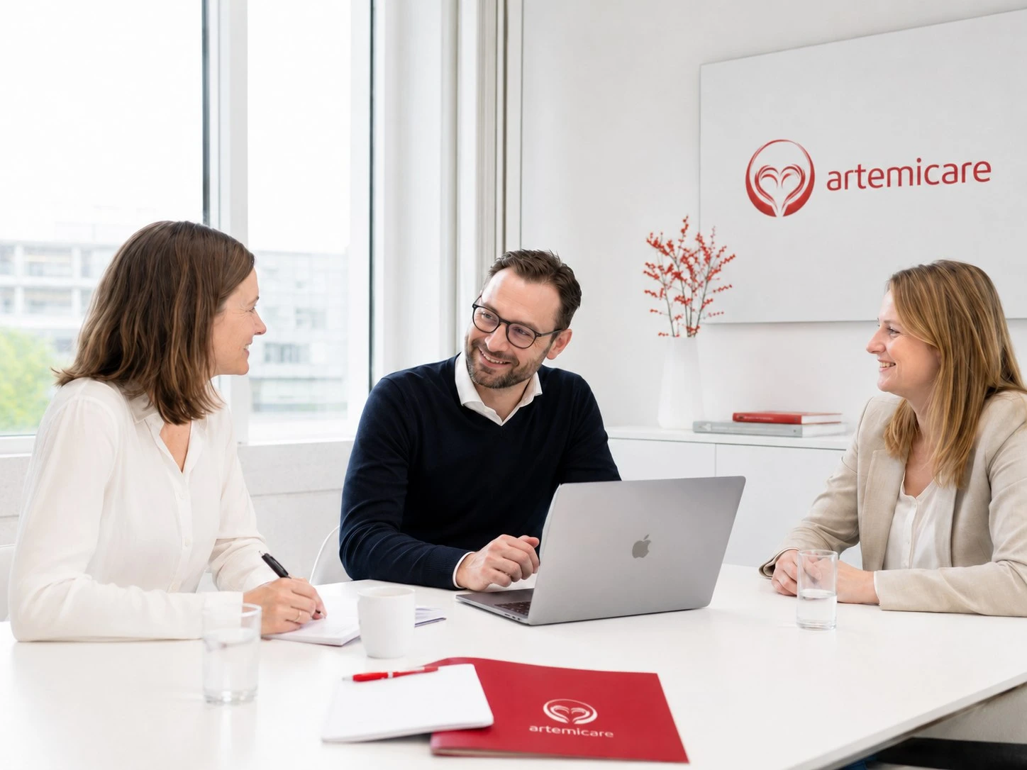 artemicare Unternehmensgespräch mit Laptop und Unterlagen